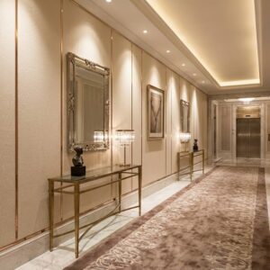 Elegancki korytarz hotelowy wyłożony jasnymi, samoprzylepnymi panelami ściennymi z pionowymi ozdobnymi listwami.